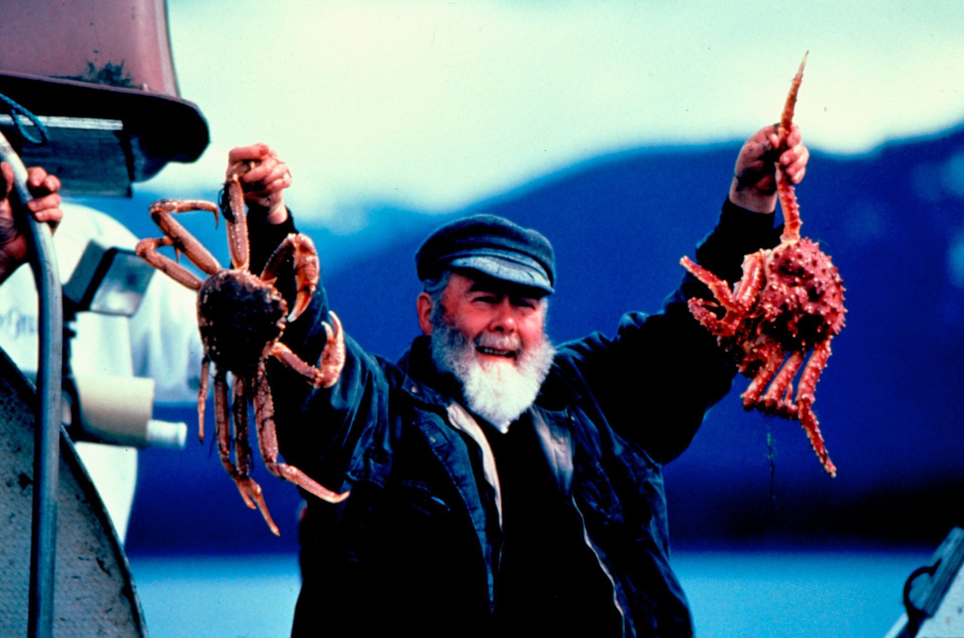 A man with a beard is holding two crabs in his hands
