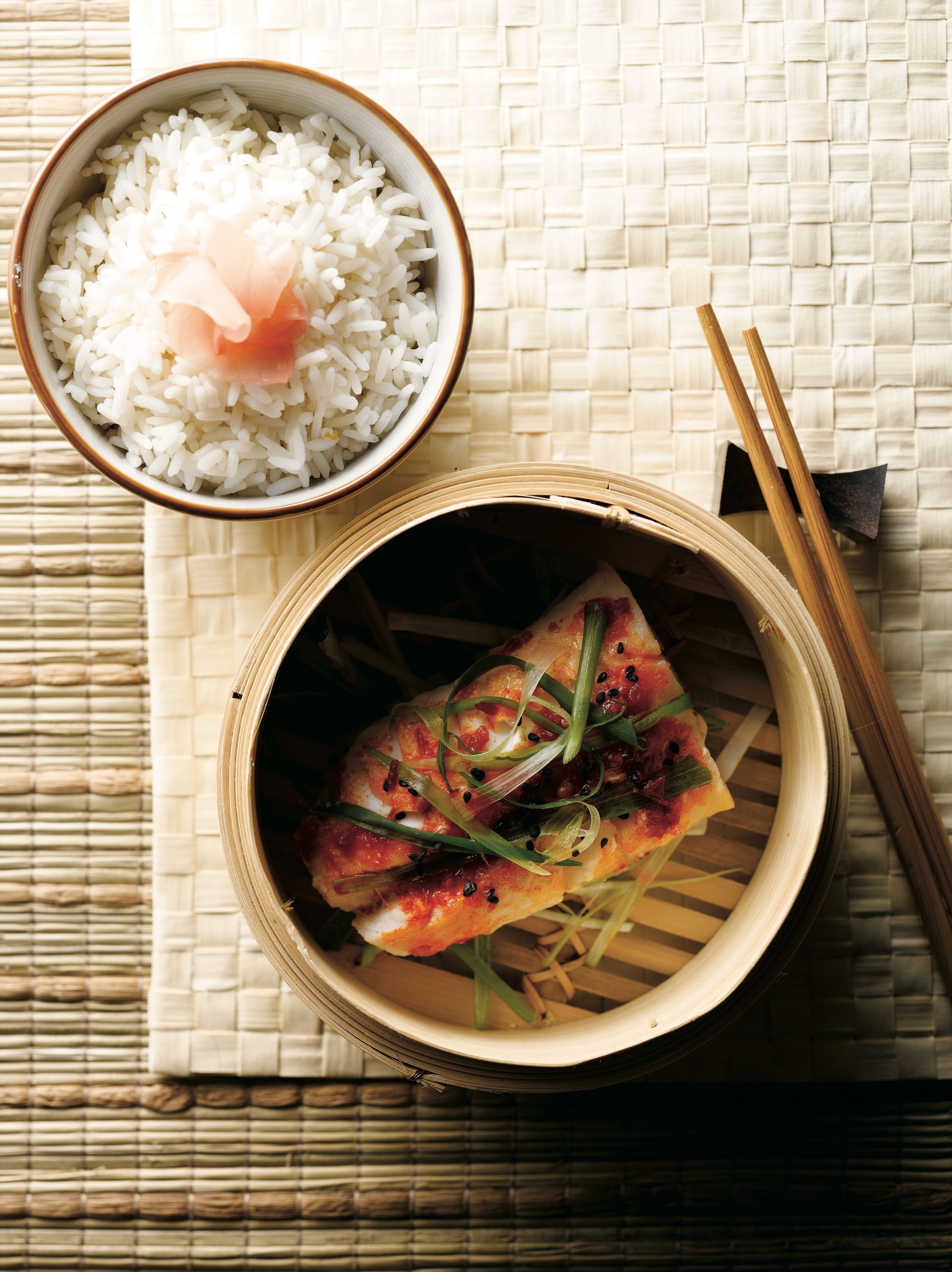 A bowl of rice next to a bowl of food with chopsticks