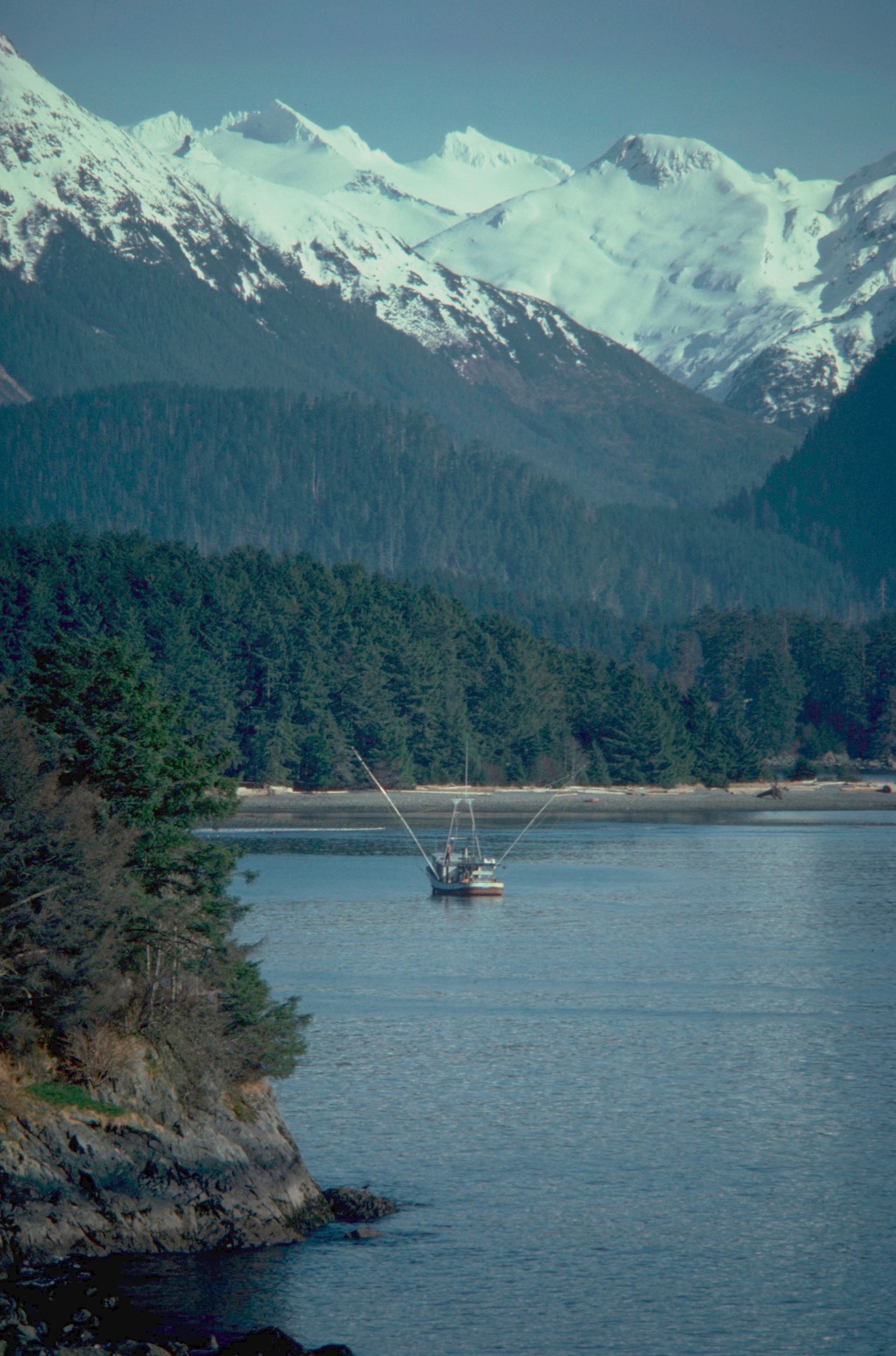 A boat is in the middle of a lake with mountains in the background.