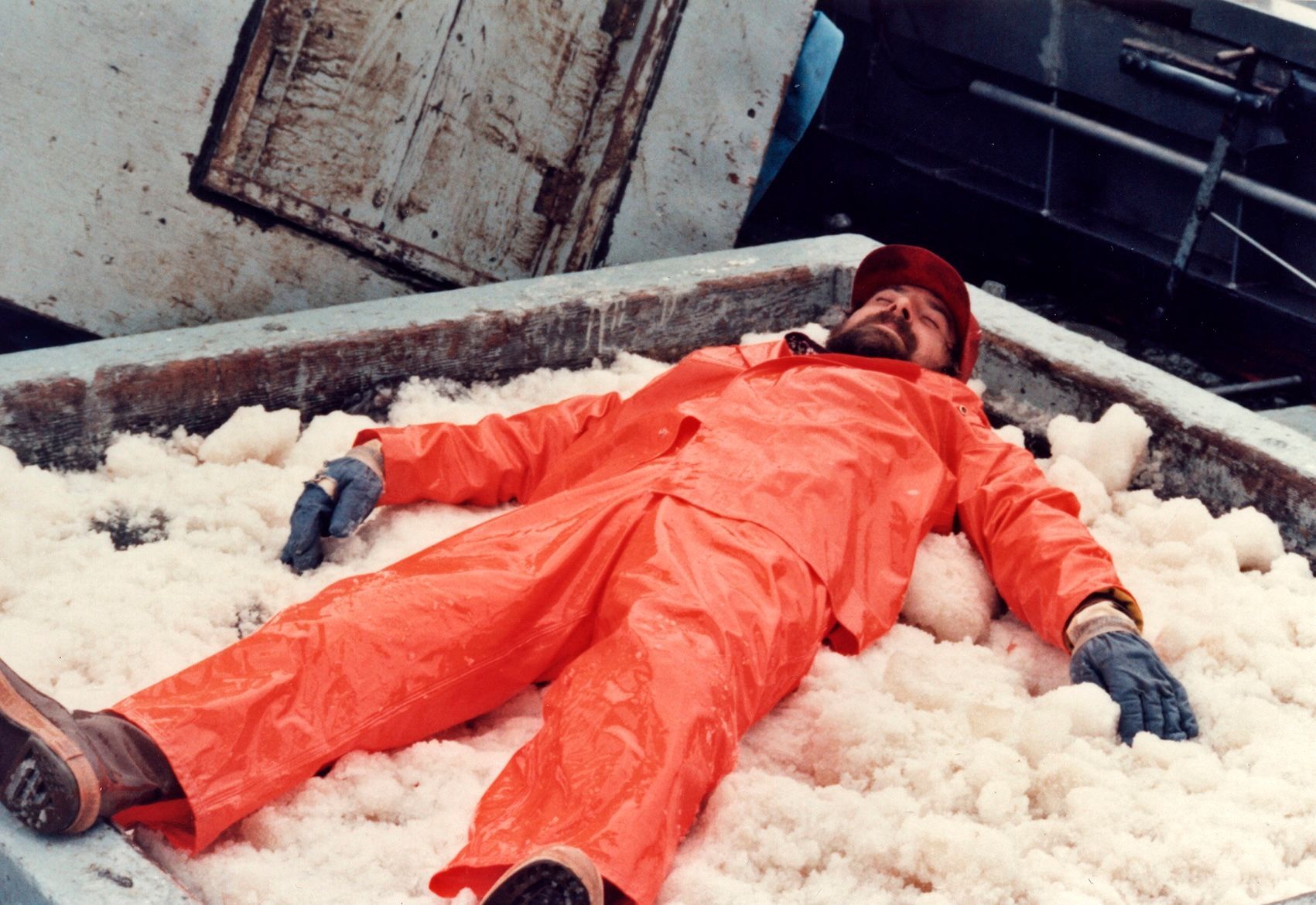 Man laying on load of fish.