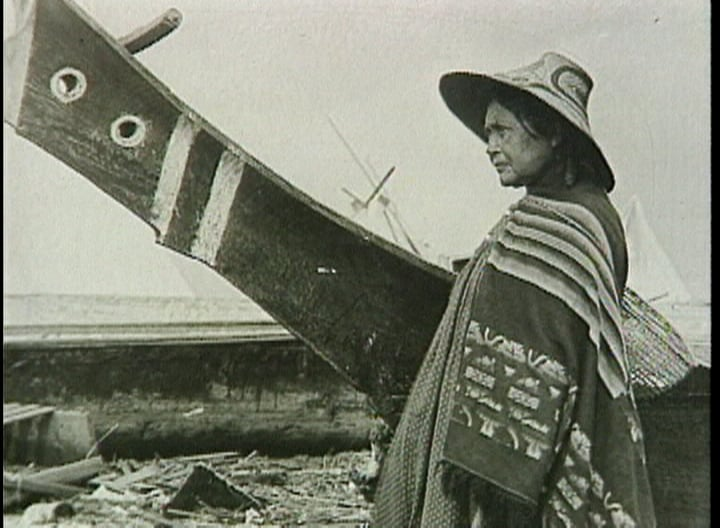 A black and white photo of a woman standing next to a boat