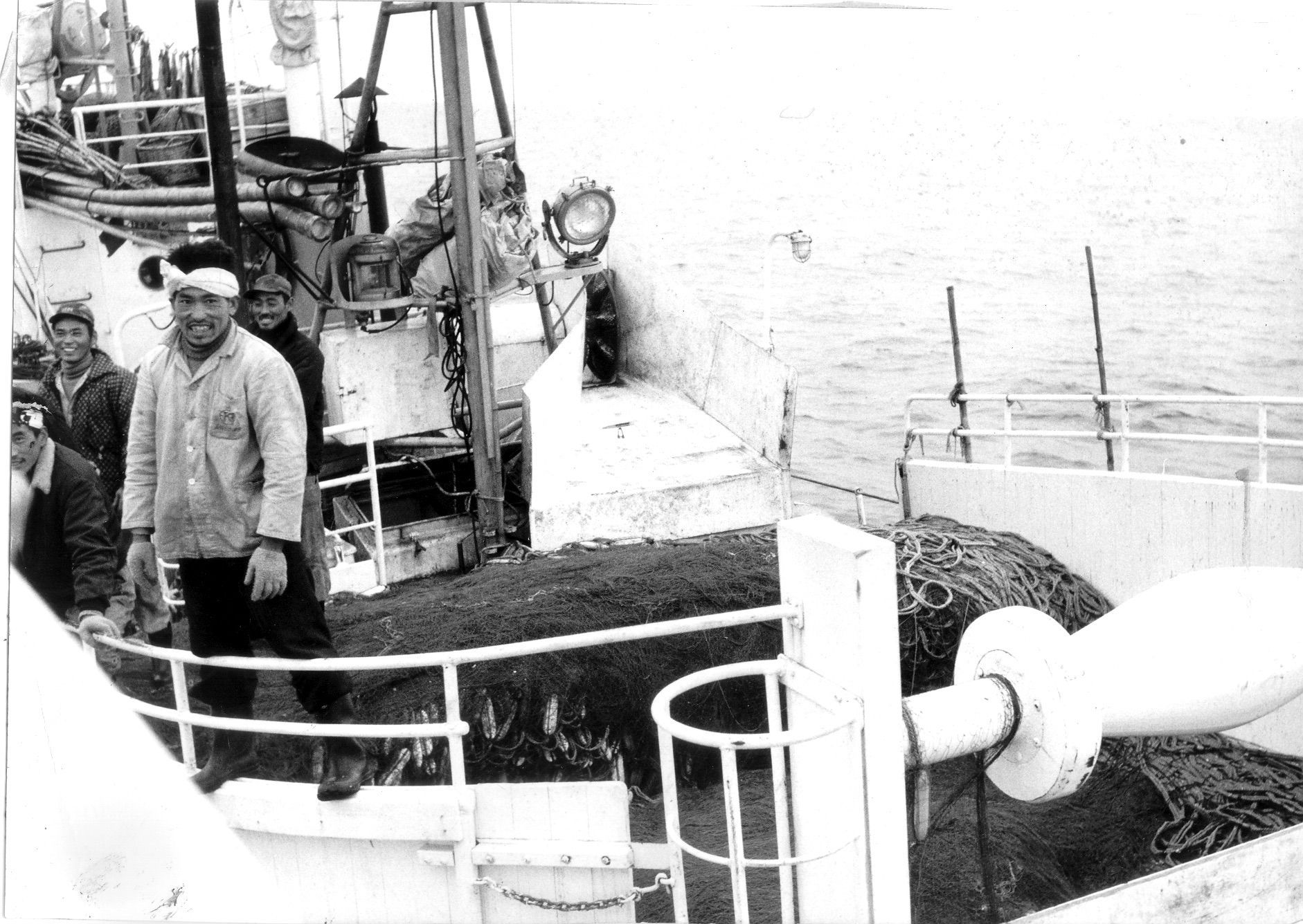 A black and white photo of a man on a boat