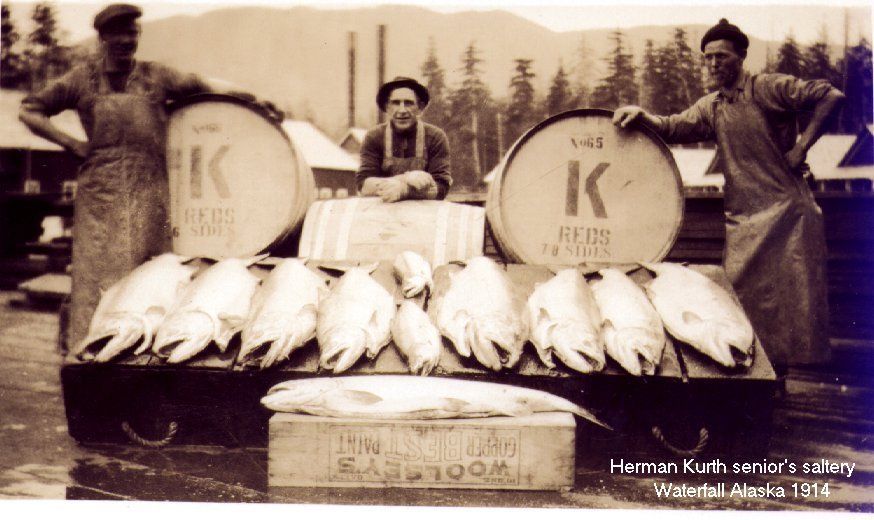 A black and white photo of three men standing next to barrels with the letter k on them
