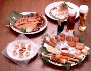 A table topped with plates of food and glasses of beer.