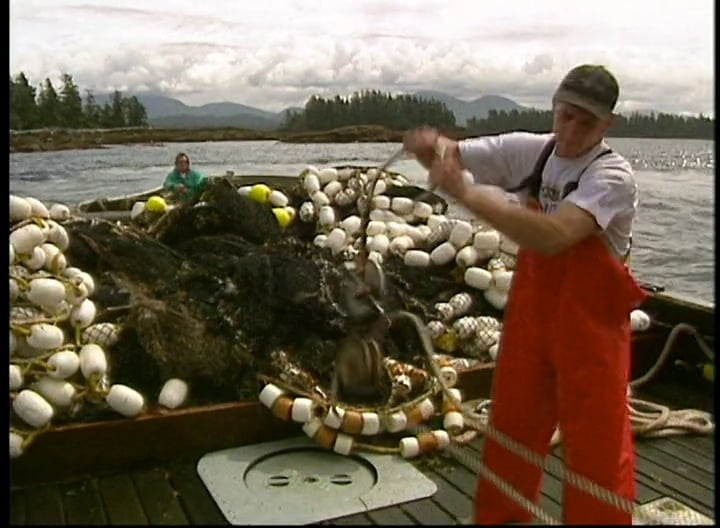 A man in red overalls is working on a boat