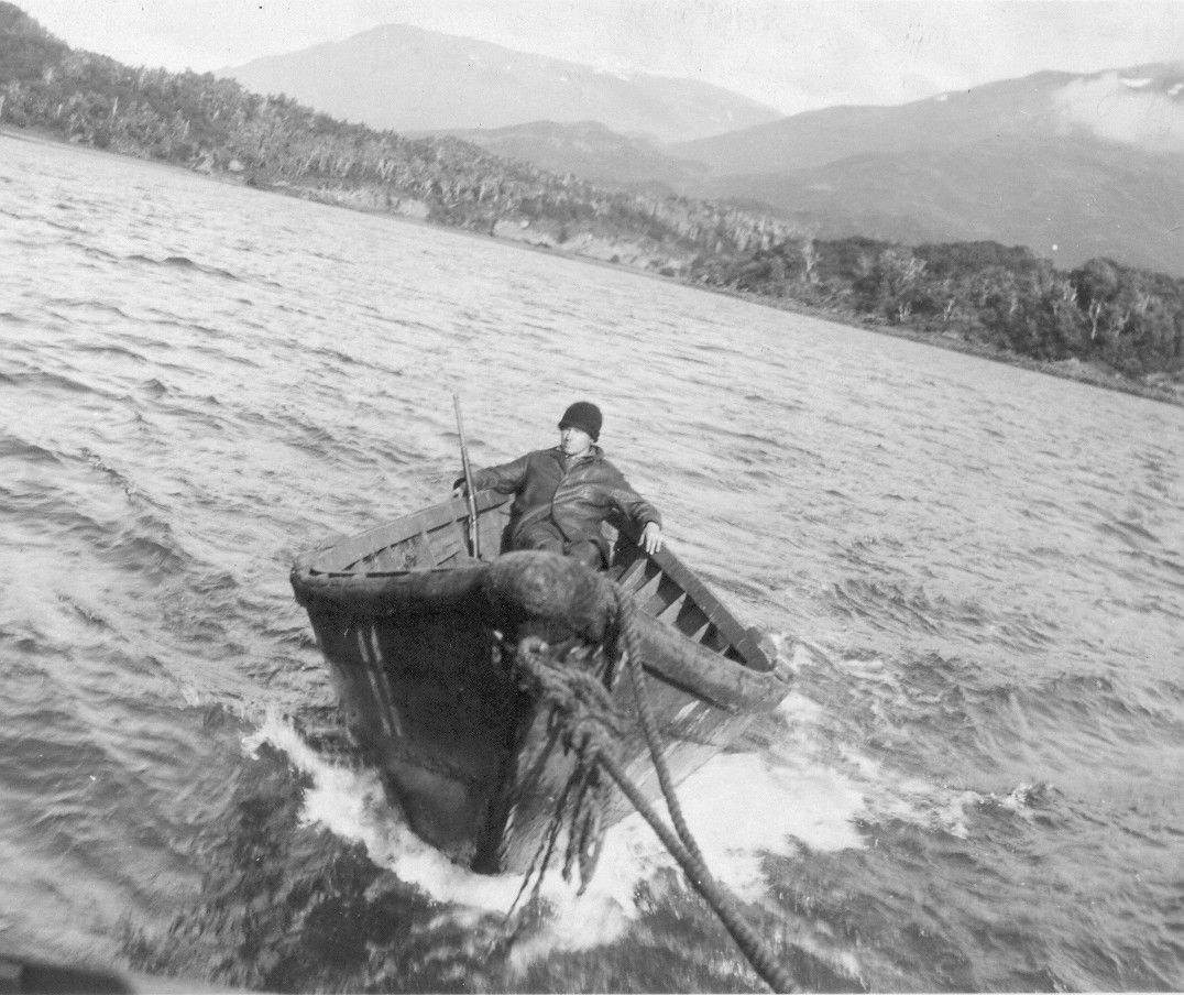 A black and white photo of a man in a boat on a lake.