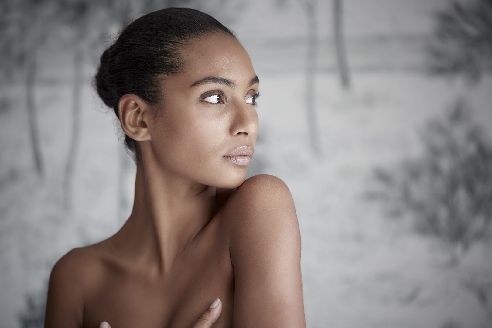 Une femme avec de la crème blanche sur le visage porte son doigt à ses lèvres.