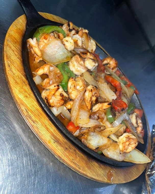 Sizzling shrimp fajitas with sliced onions and colorful bell peppers served on a hot cast-iron skillet.