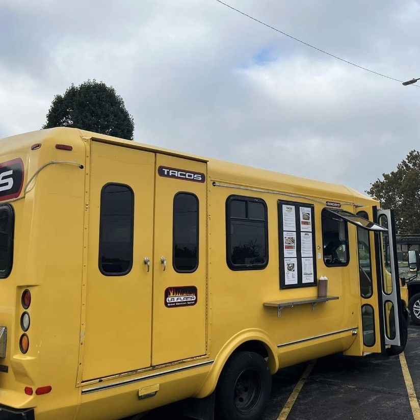 A yellow food truck with a serving window, parked outdoors on a paved lot.