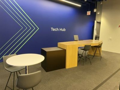 A room with a table and chairs in front of a wall that says tech hub