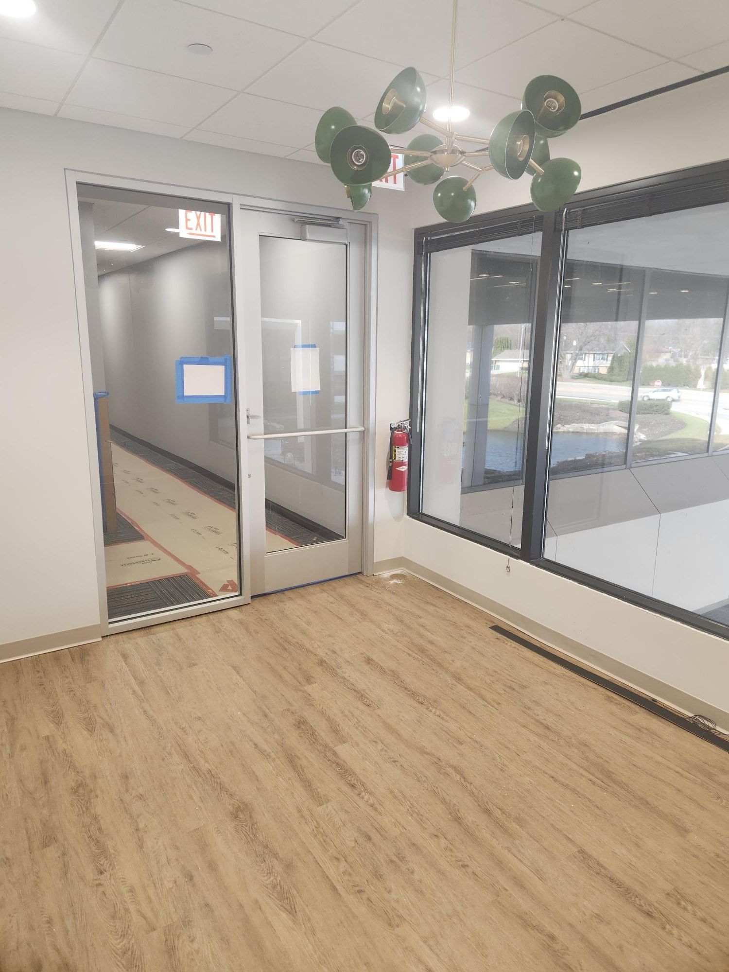 A hallway with a glass door and balloons hanging from the ceiling.