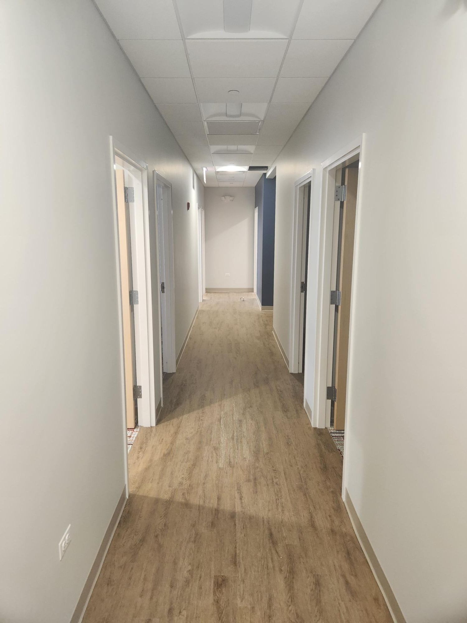 A long hallway with wooden floors and white walls.