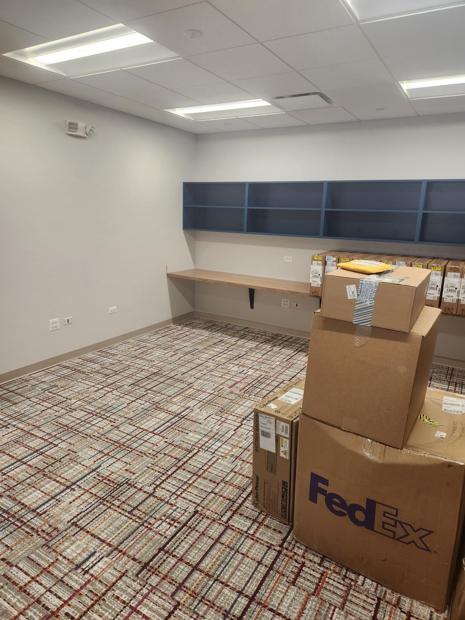 A room with a stack of fedex boxes on the floor.