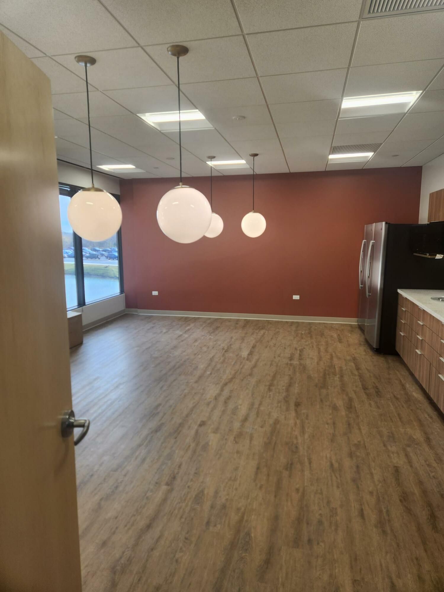 A large empty room with a wooden floor and a red wall.