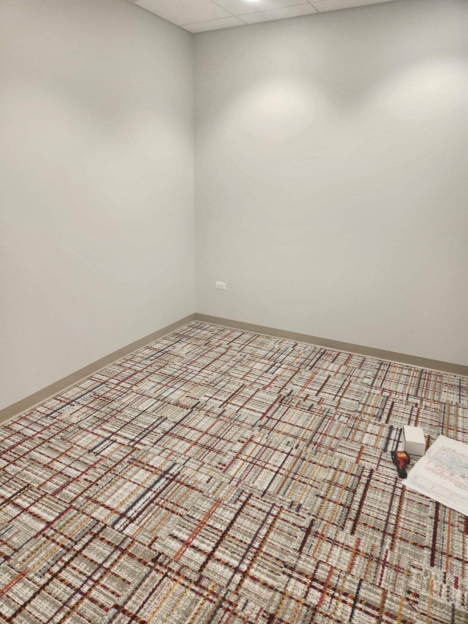 An empty room with a carpeted floor and white walls.