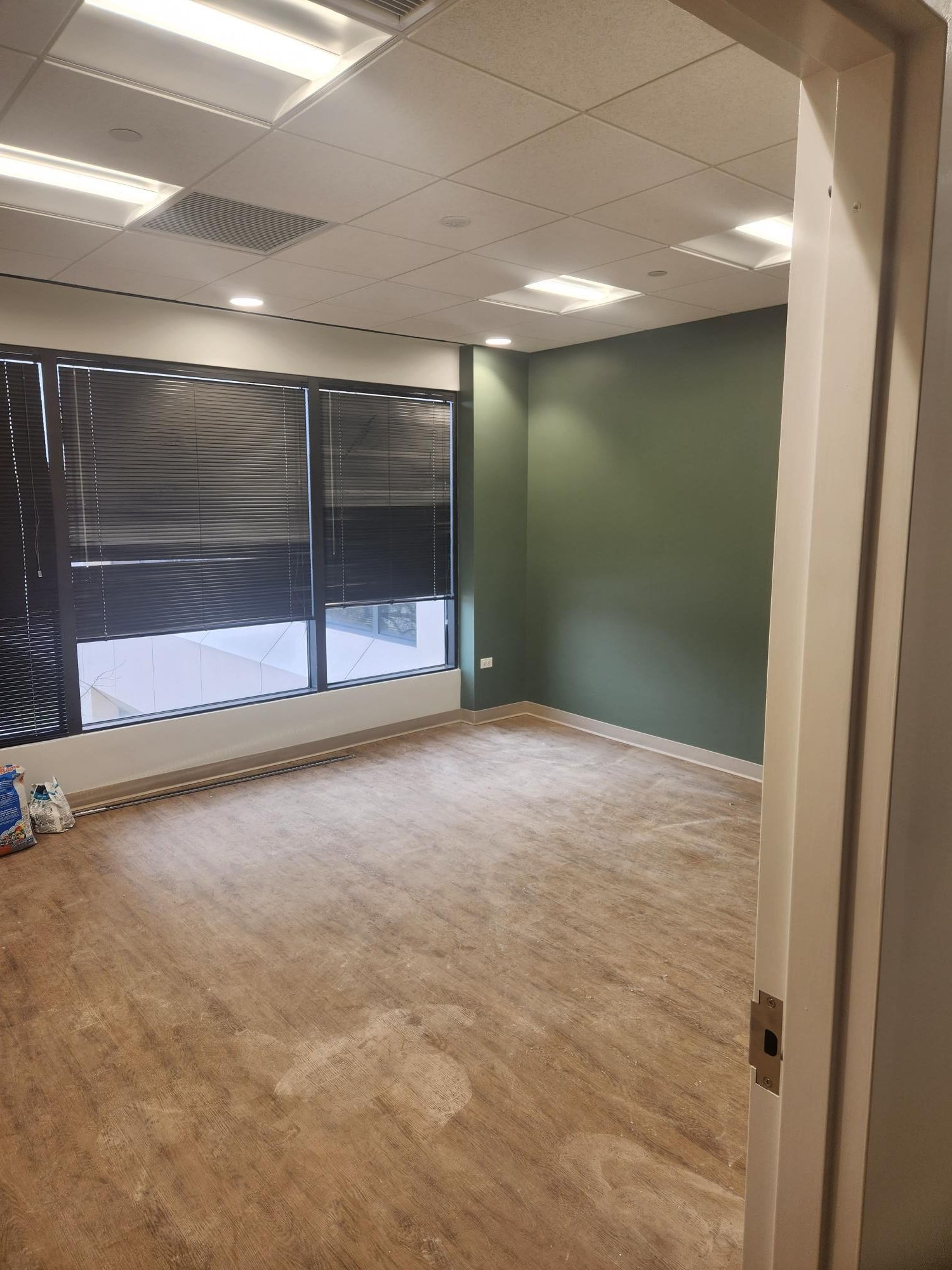 A large empty room with a wooden floor and a window.