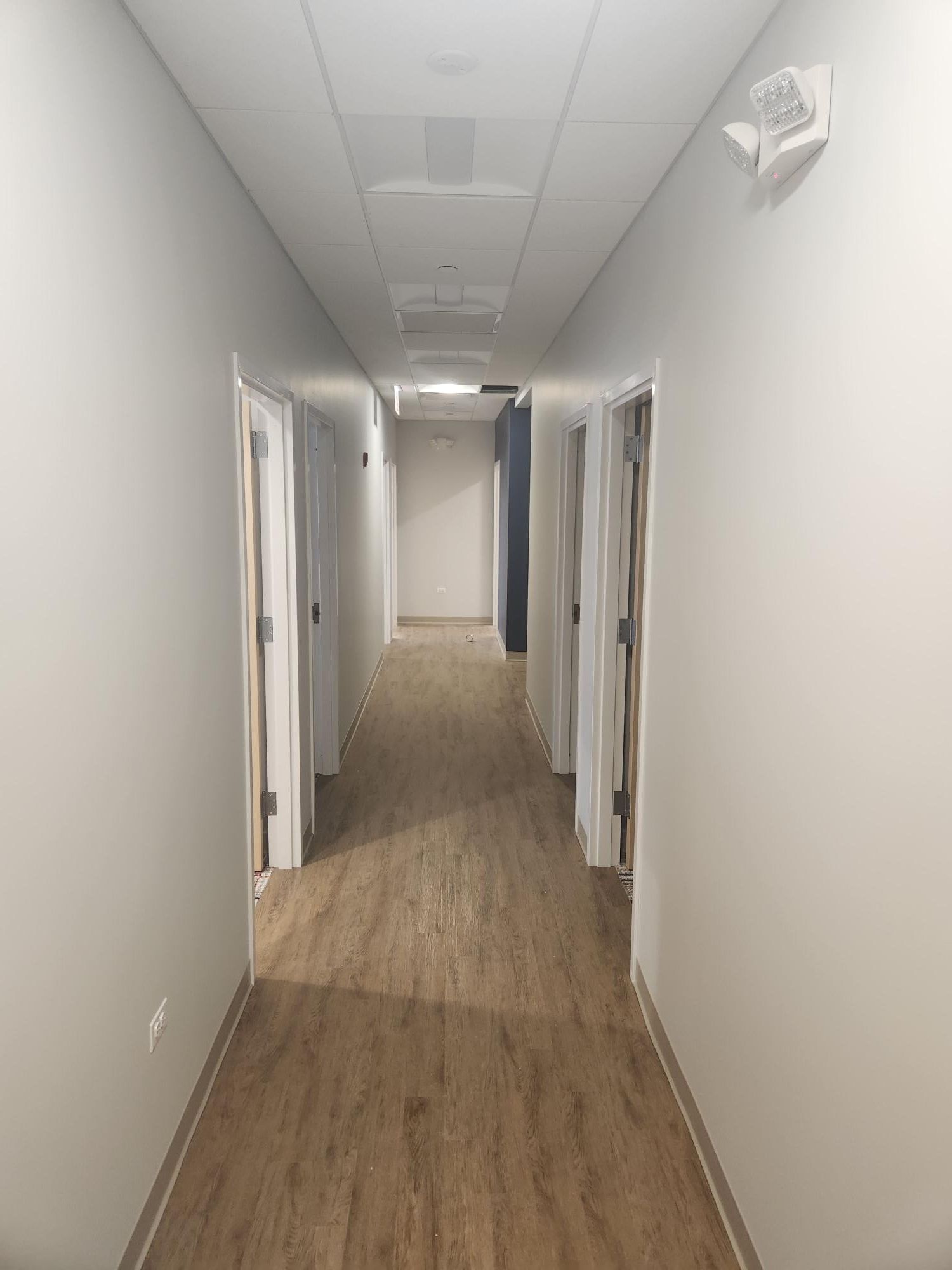 A long hallway with wooden floors and white walls.