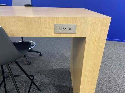 A wooden table with a socket on the side of it.