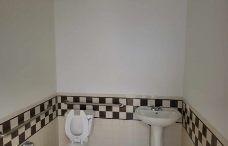 A bathroom with a toilet , sink and checkered tiles.