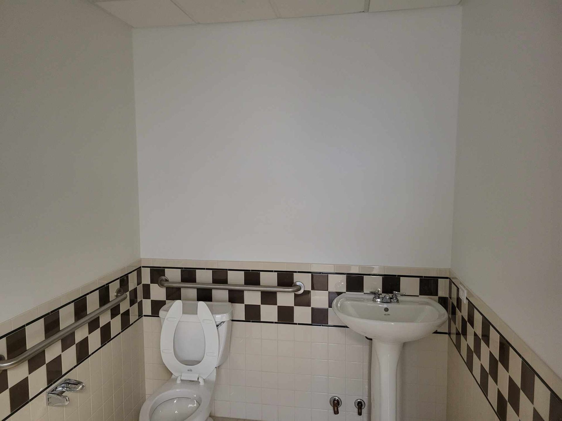 A bathroom with a toilet a sink and a checkered wall