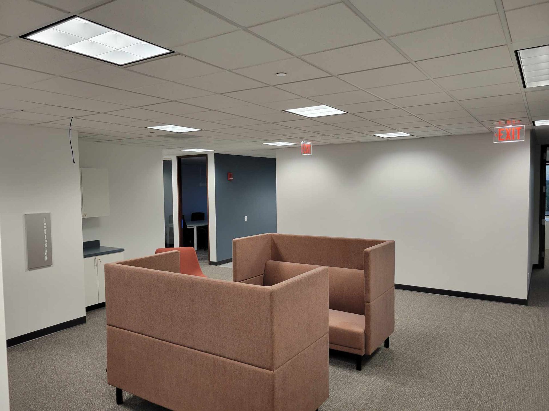 An empty room with two couches and a red exit sign