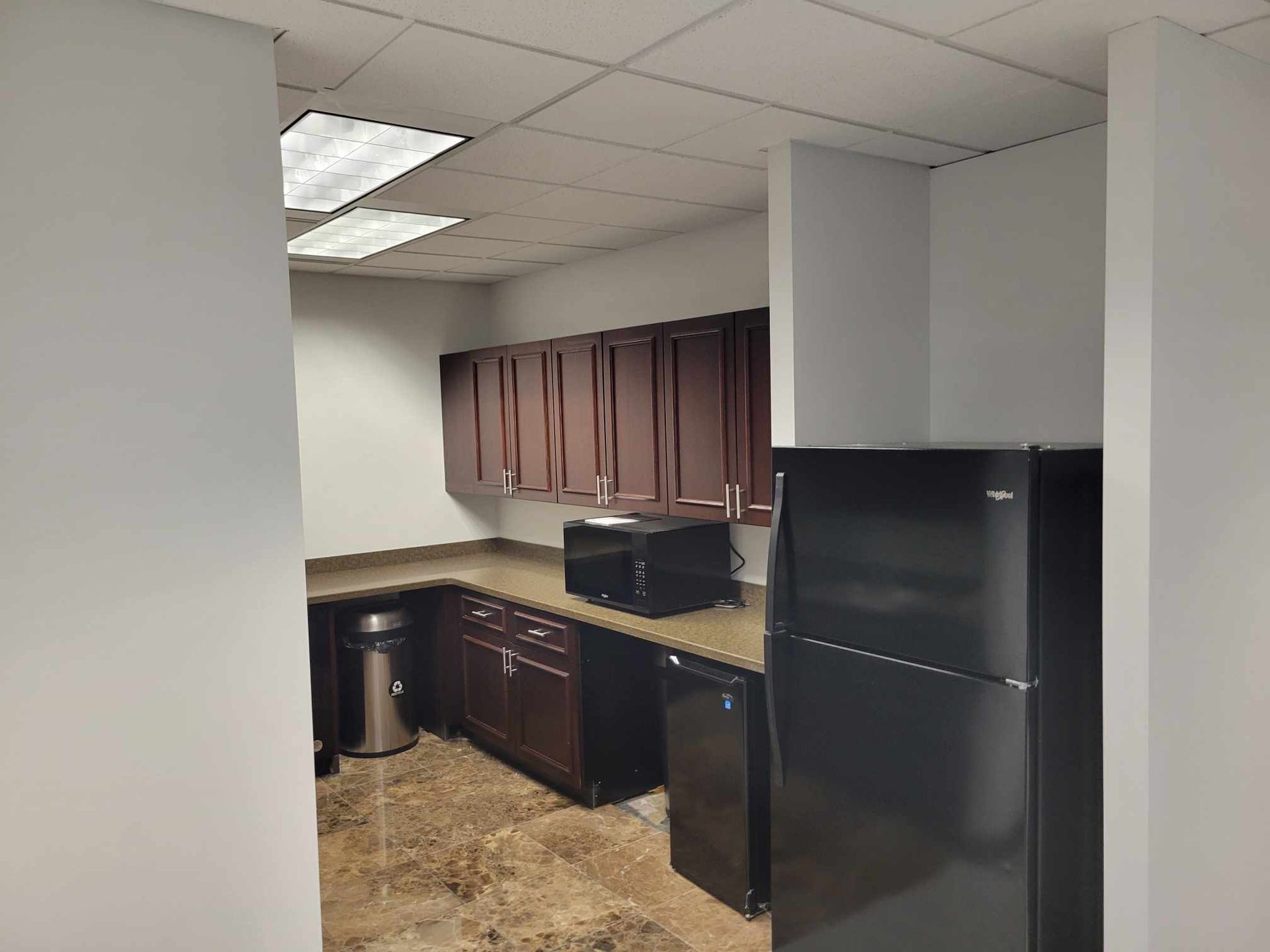 A kitchen with black cabinets and a black refrigerator