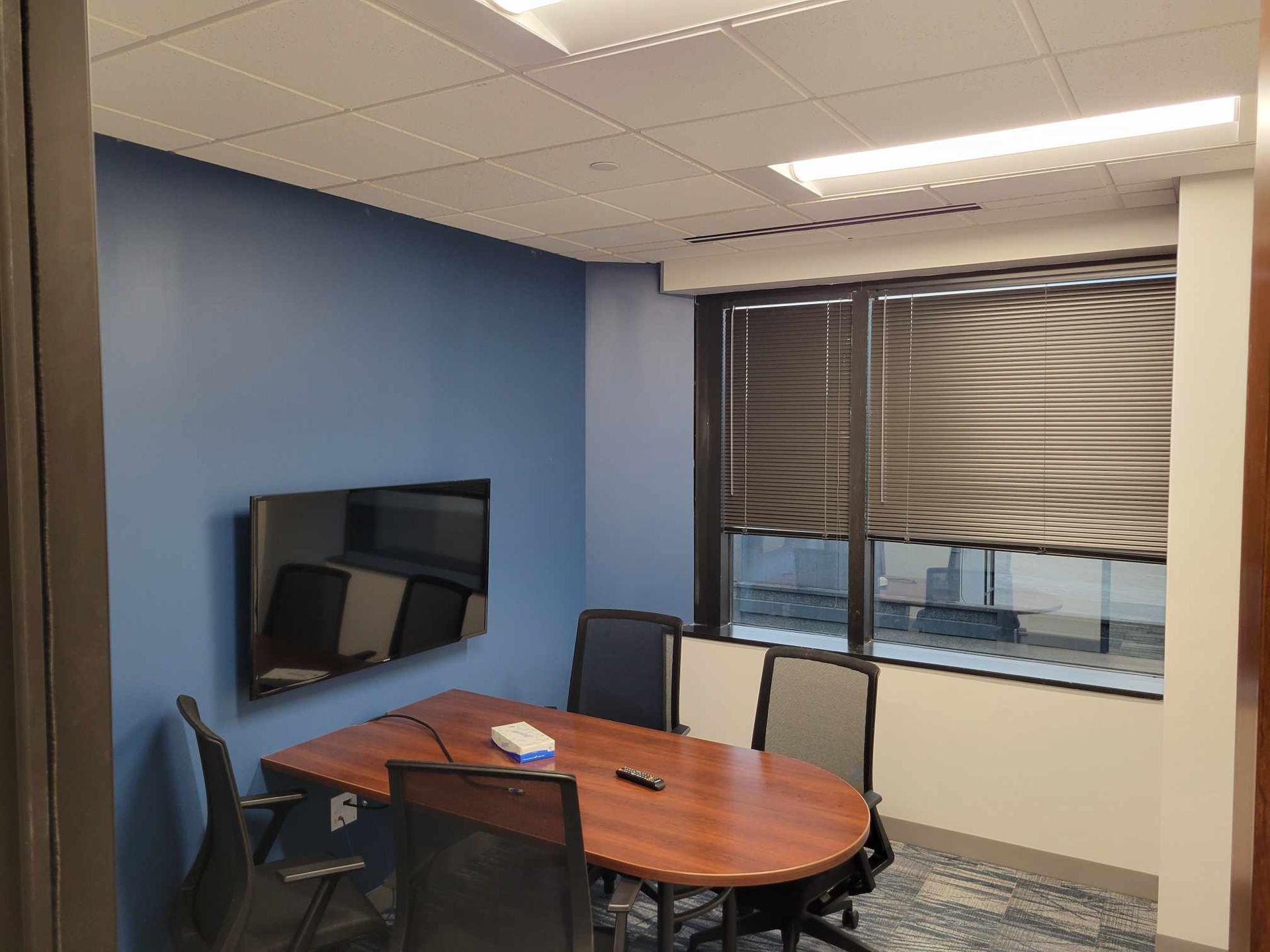 A conference room with a table , chairs and a flat screen tv.