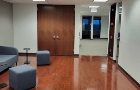 A room with hardwood floors and a couch and ottomans