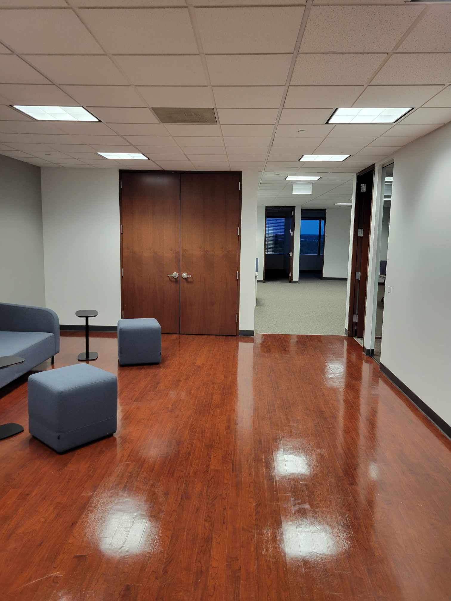 A large room with hardwood floors and a couch and ottomans