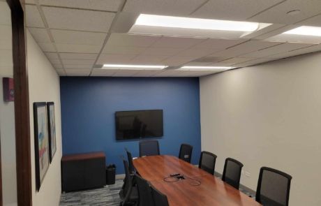 A conference room with a long table and chairs and a flat screen tv on the wall.