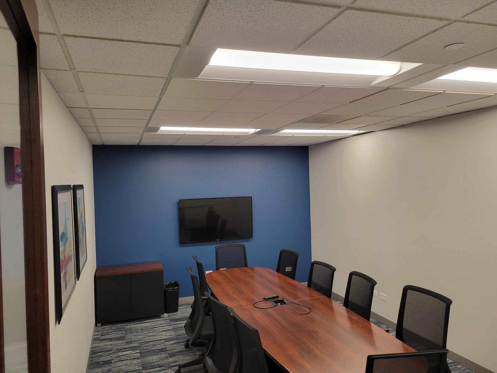 A conference room with a long table and chairs and a flat screen tv on the wall.