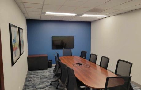 A conference room with a long table and chairs and a flat screen tv.
