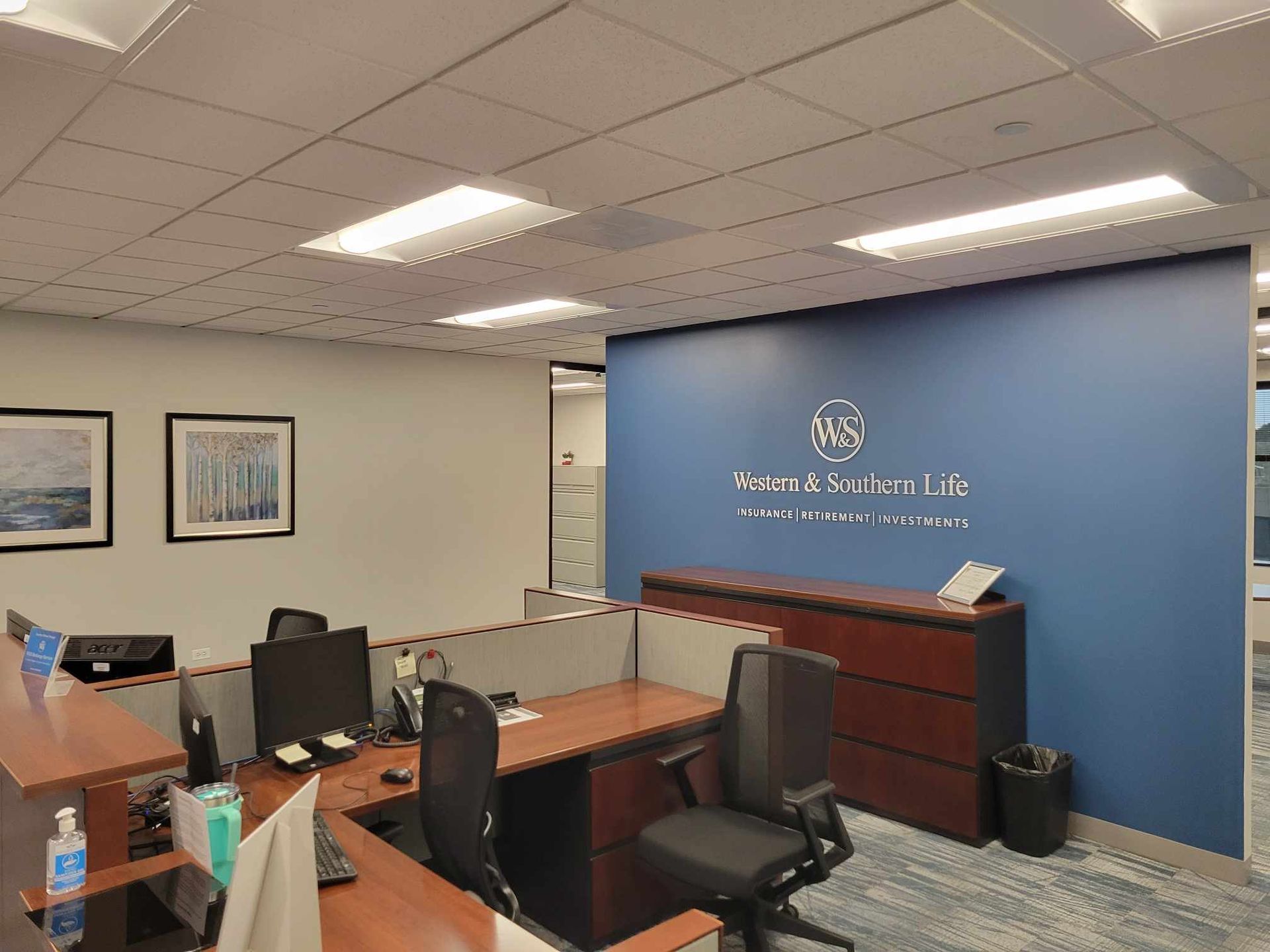 A large office with a blue wall , desks , chairs and computers.