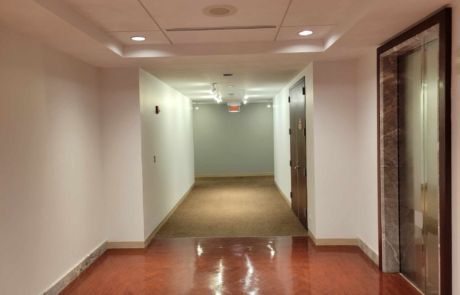 A long hallway with a red floor and white walls