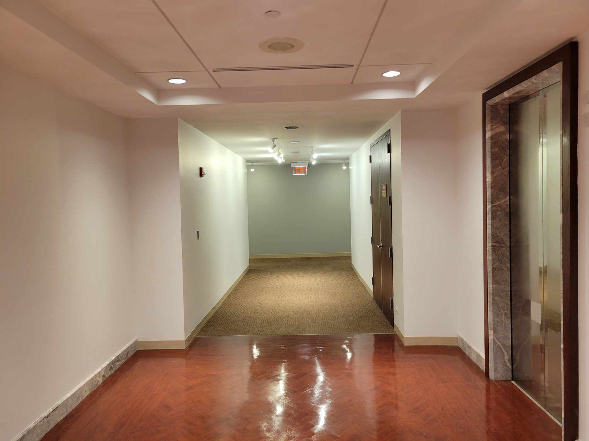 A long hallway with a red floor and white walls