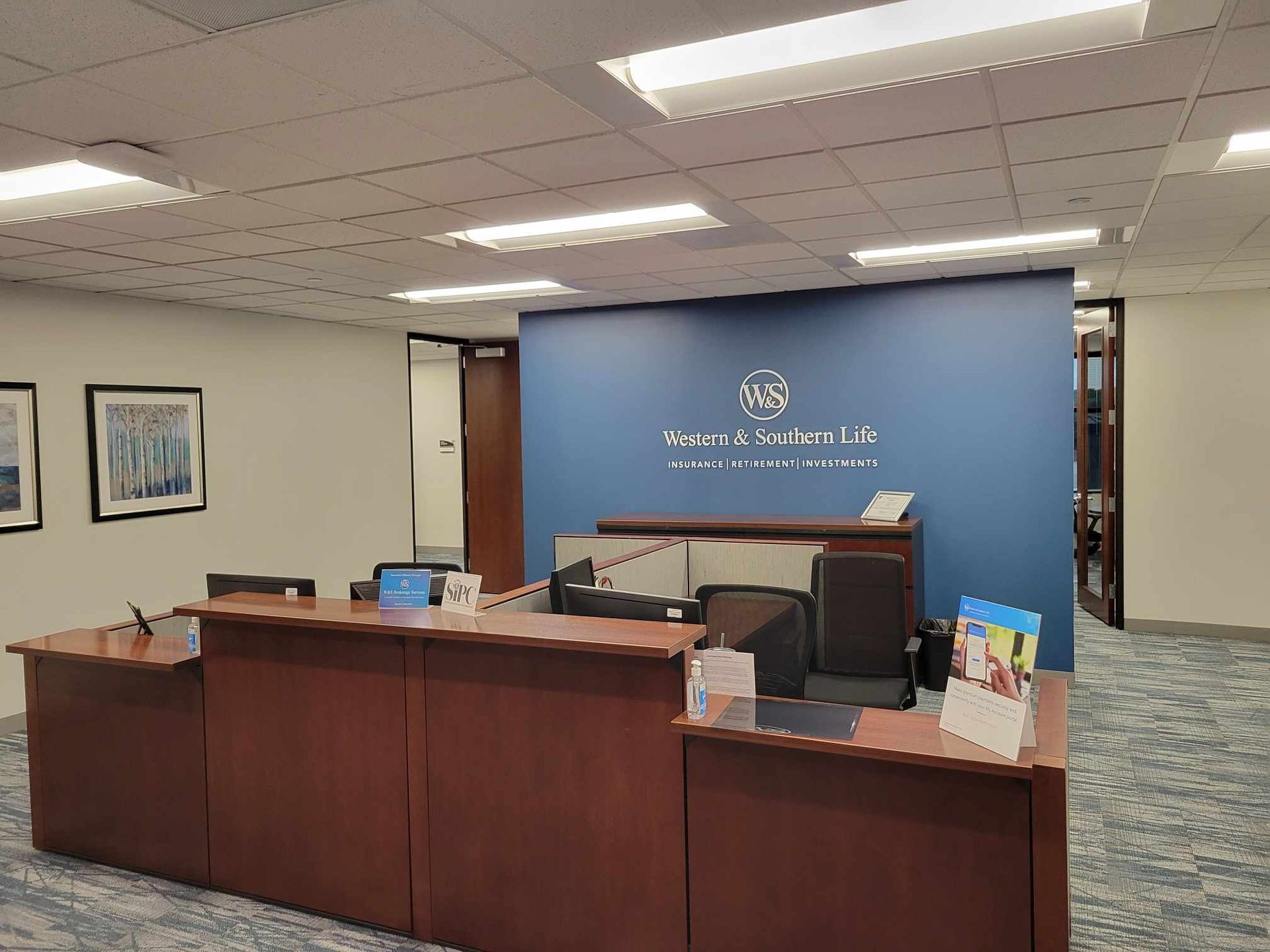 A reception area in an office with a blue wall and a wooden desk.