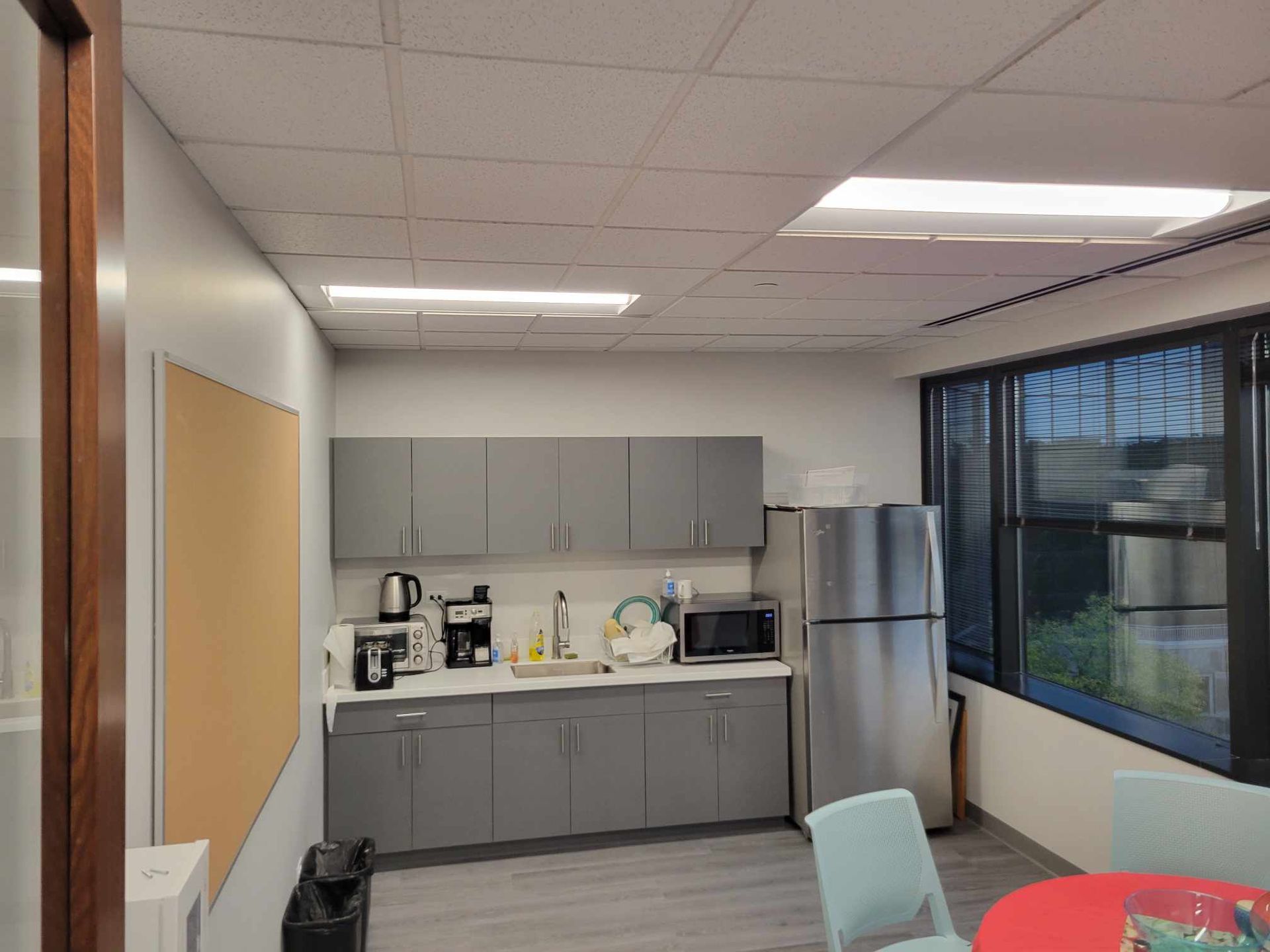 A kitchen with a refrigerator , microwave , coffee maker , and a table.