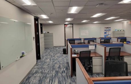 A large office with cubicles and a whiteboard on the wall.