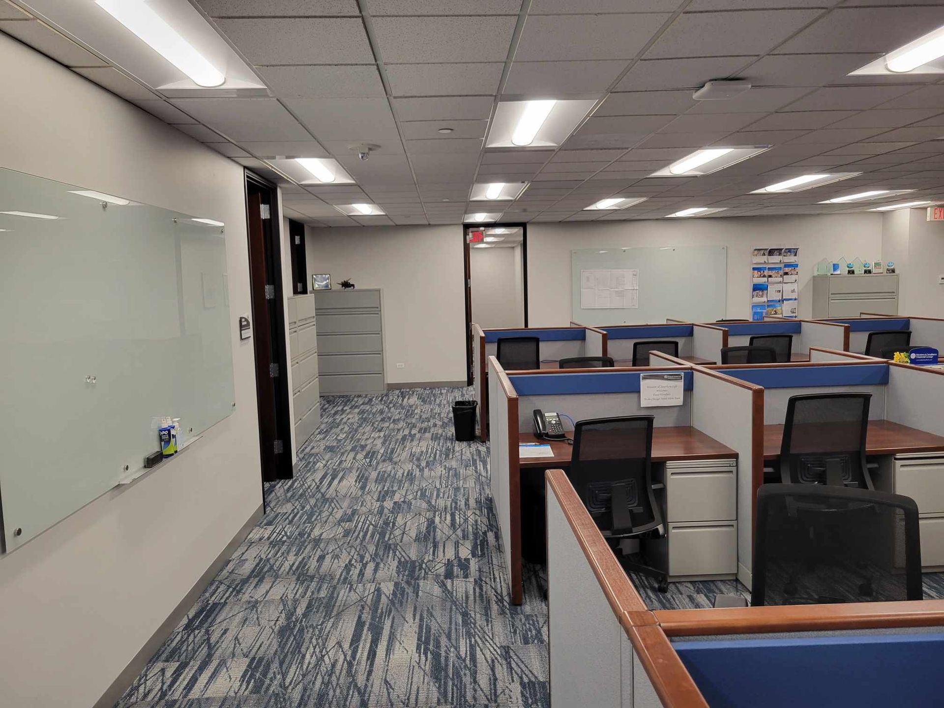 A large office with cubicles and a whiteboard on the wall.