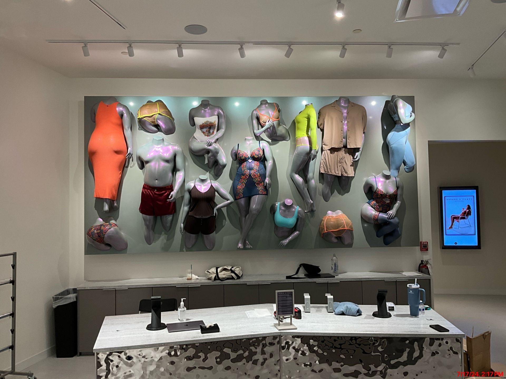 A room with a lot of mannequins on the wall and a table