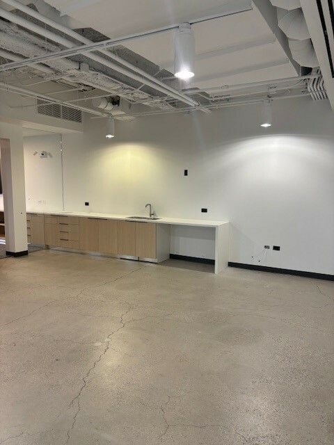 A large empty room with a sink and cabinets