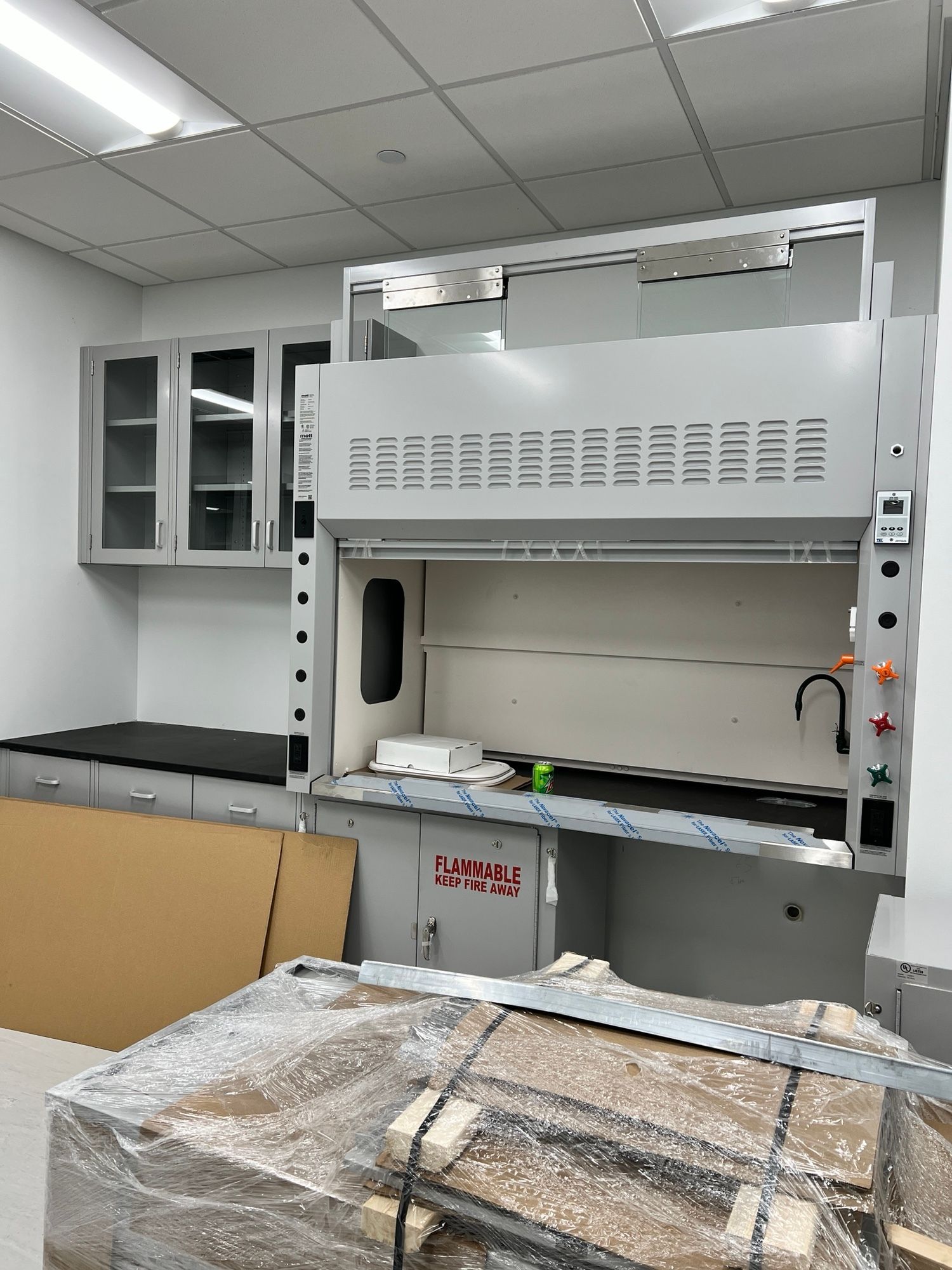 A room with a sink and cabinets and a stack of cardboard boxes on the floor.