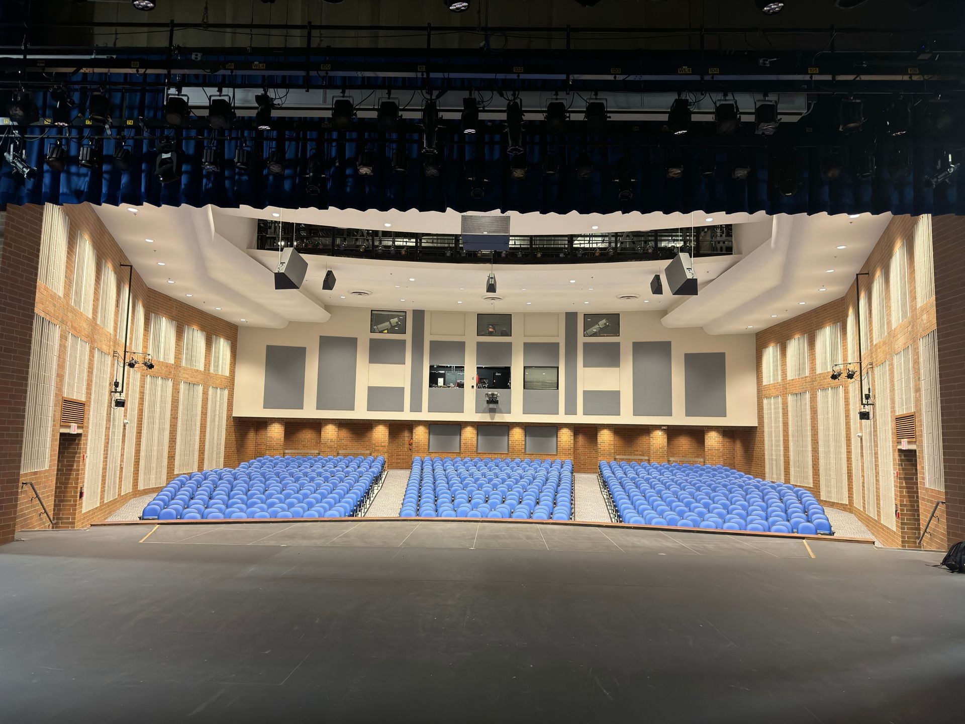 A large auditorium with blue seats and a stage
