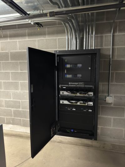 A brick wall with a black cabinet with the door open
