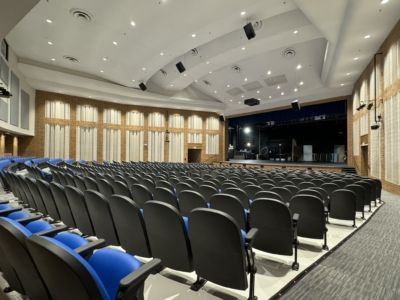 A large auditorium with blue seats and a stage