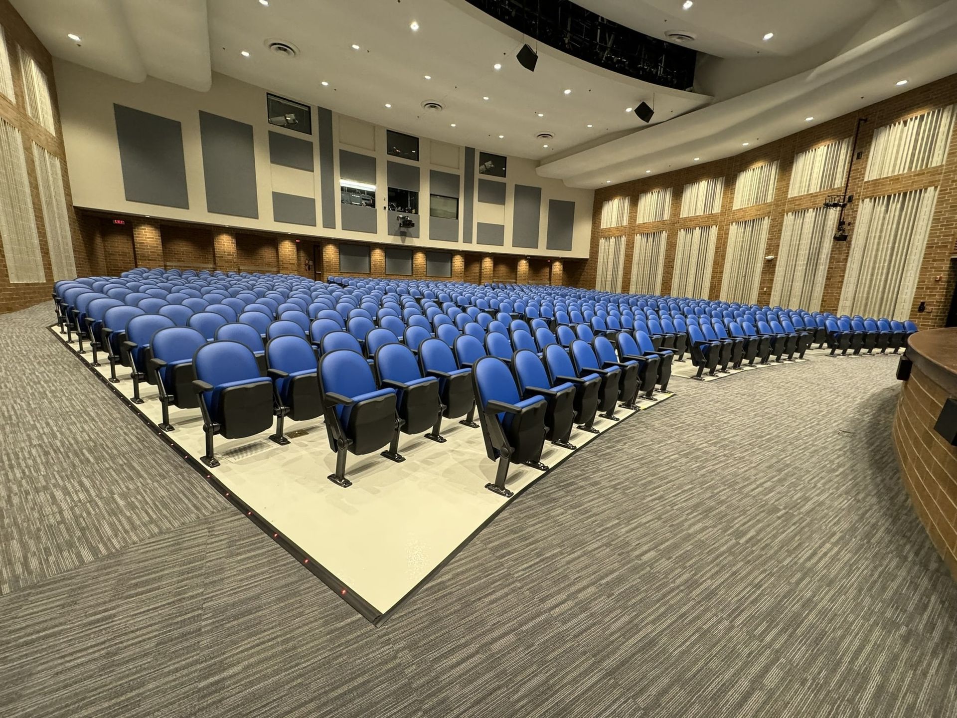 A large auditorium filled with blue chairs and a stage.