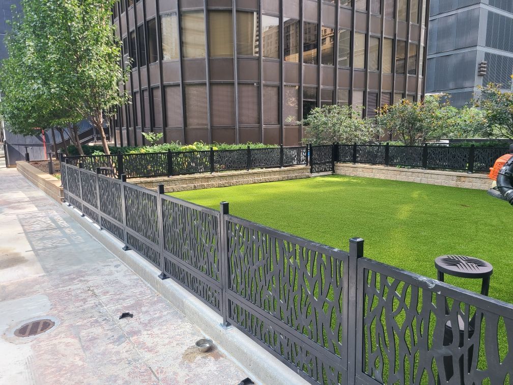 A fence surrounds a grassy area in front of a building.