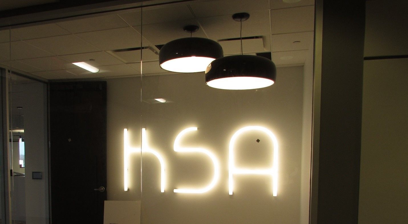 A neon sign that says ksa is lit up in a dark room