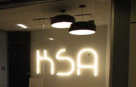 A neon sign that says ksa hangs from the ceiling