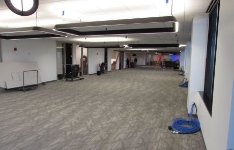 A large empty room with a lot of windows and a hose on the floor.